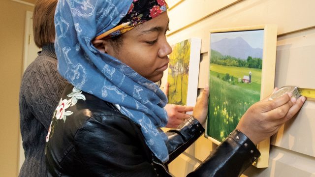 Female student places photo in an art gallery