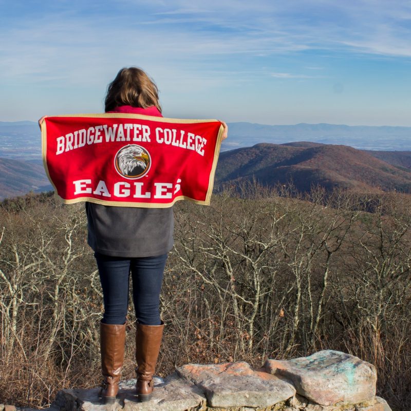 Student at Reddish Knob holding Bridgewater College flag