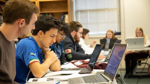 Students study in class behind laptops