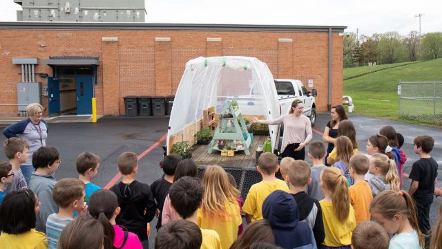 Group of children looking at a greenhouse on a trailer