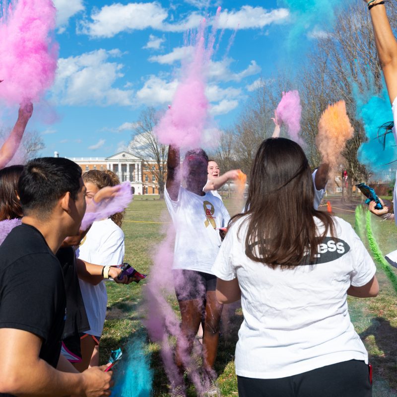 Students throwing bright pink and blue chalk in the air