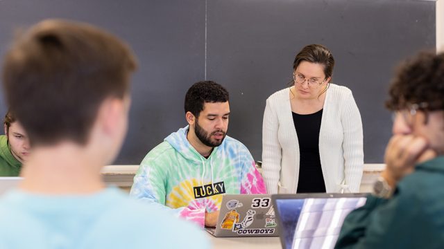 Professor helping student in bright tie dye sweatshirt