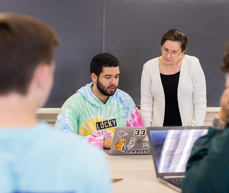 Professor helping student in bright tie dye sweatshirt