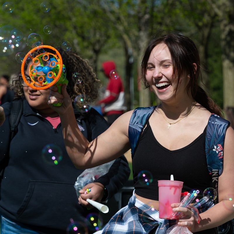 Female student smiling while playing with bubbles
