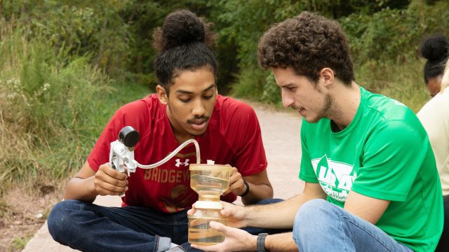 Two students using equipment for an environmental science project