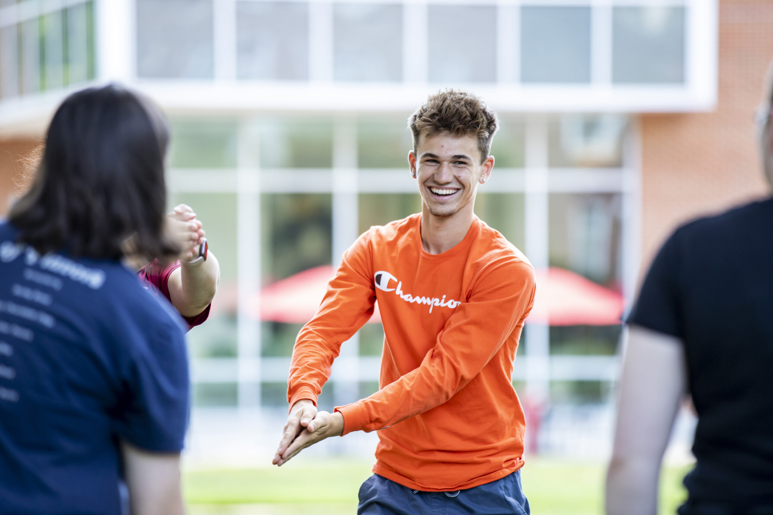 Student wearing orange shirt playing a game during orientation
