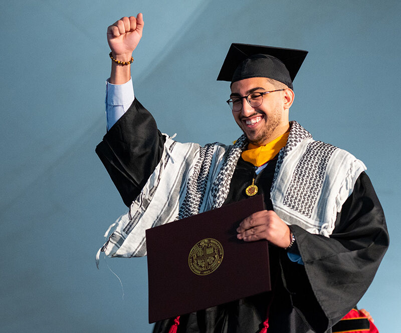 Student raising fist in the air out of excitement he just graduated