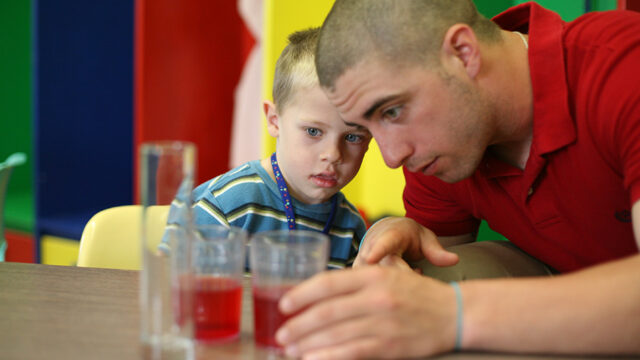 Student teacher working with a child on a science experiment