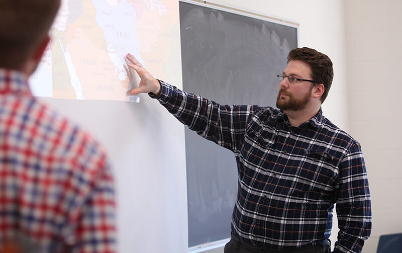 Student standing pointing to map projected on a screen