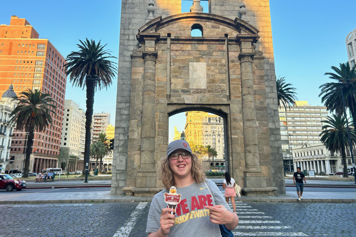 Student wearing We are Bridgewater shirt holding a flat Ernie in Uruguay