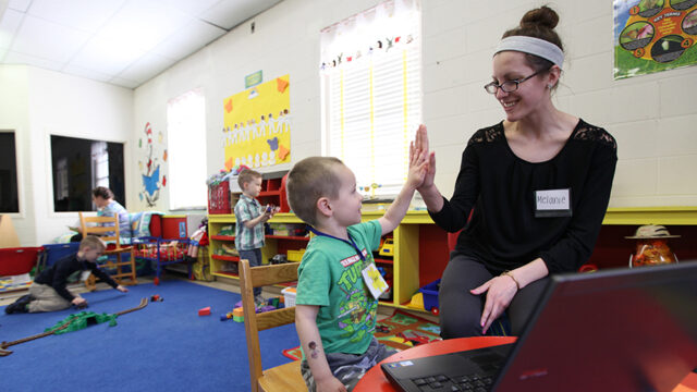Education student high fiving little boy in the child development laboratory