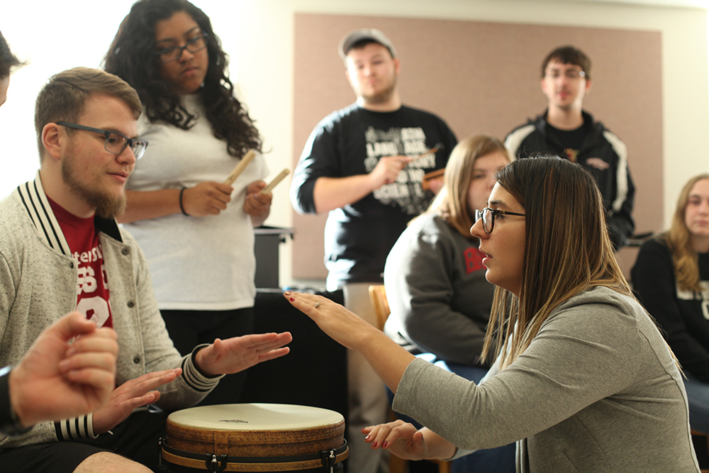 Music professor teaching student how to play a drum 