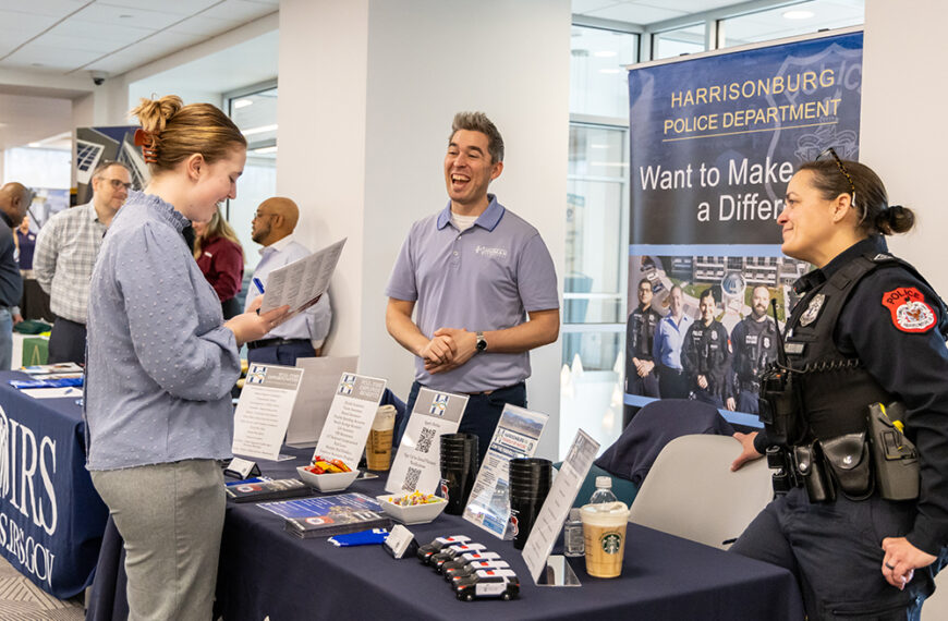 Student speaking with members of the Harrisonburg police department at a career fair