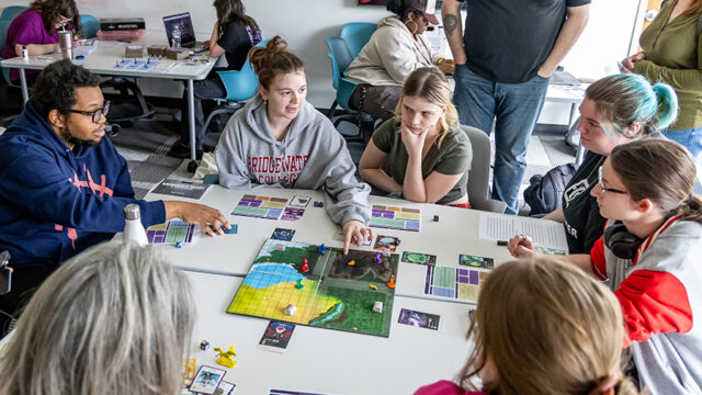 Group of students playing a board game designed in a game design class