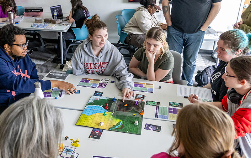 Group of students playing a board game designed in a game design class