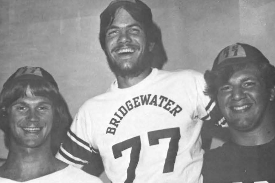 Photo from 1974 of a student wearing a Bridgewater shirt with the number 77 and two students standing next to him