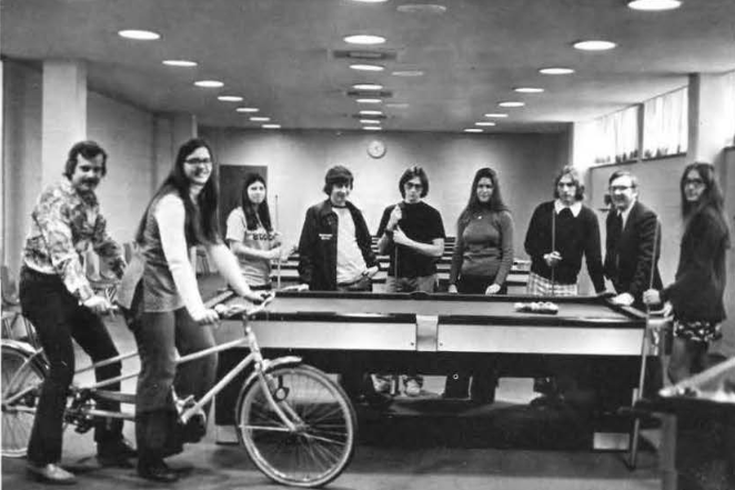 Photo from 1975 yearbook of students standing around a pool table