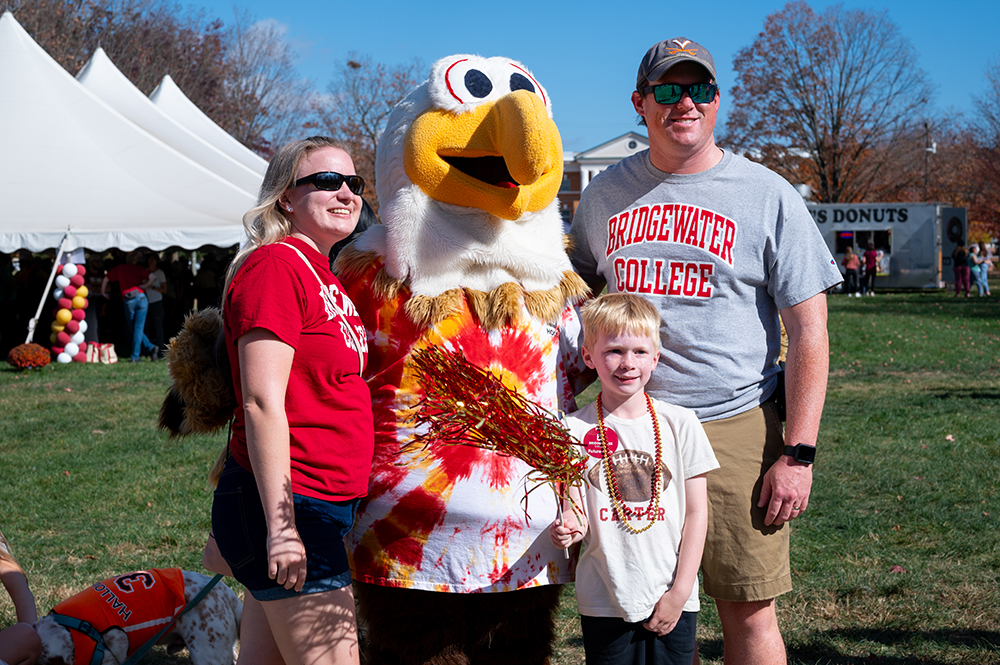 Mom Dad and son standing with mascot Ernie for a photo