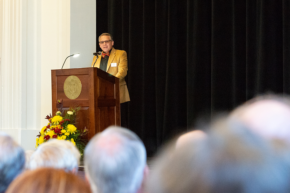 Man in gold jacket speaking at a podium