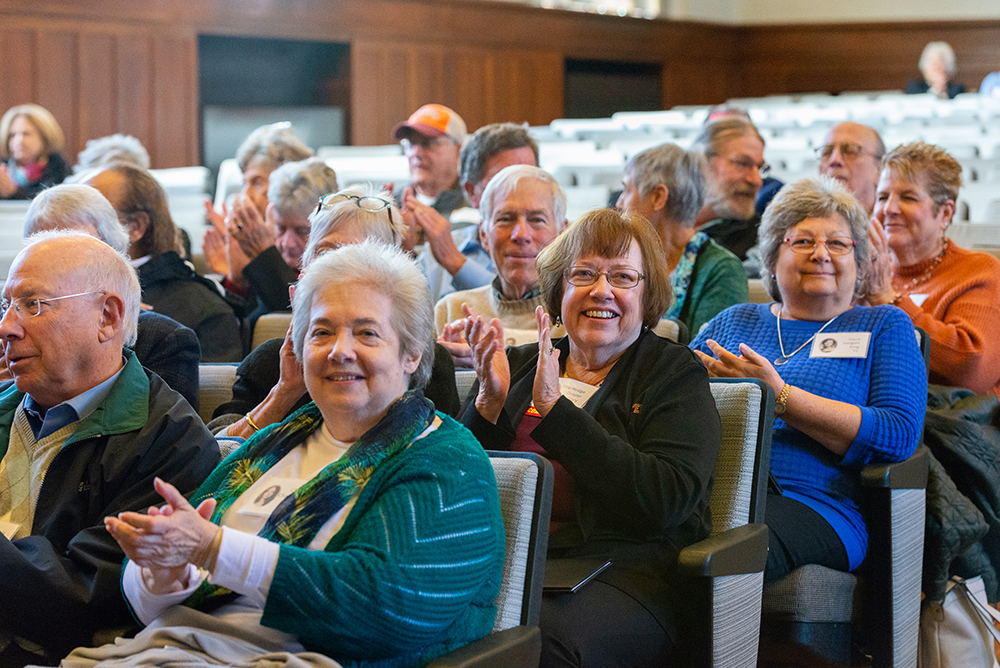 Group of people sitting in auditorium chairs clapping and smiling