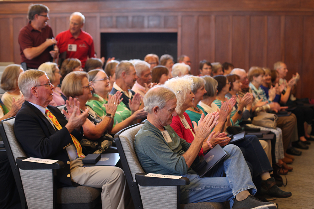 50th reunion group sitting in auditorium chairs giving an applause