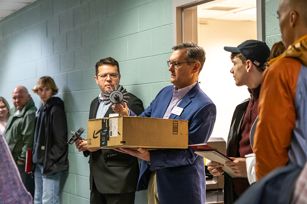 Dr. Phil Spickler holding box and engineering equipment during engineering department tour