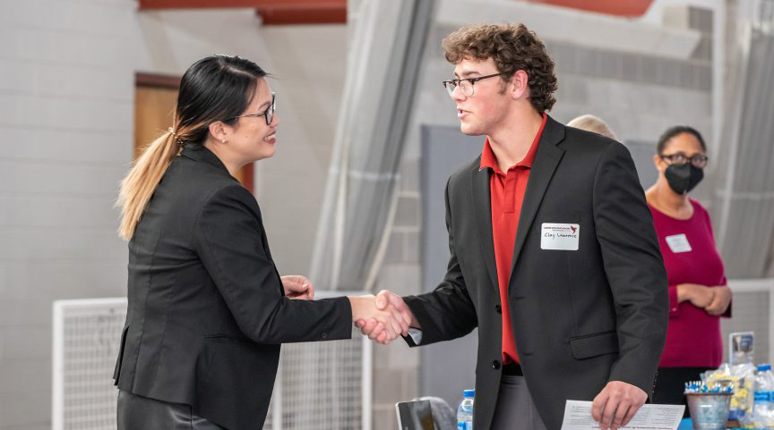 Student and job recruiter shake hands at career exploration day