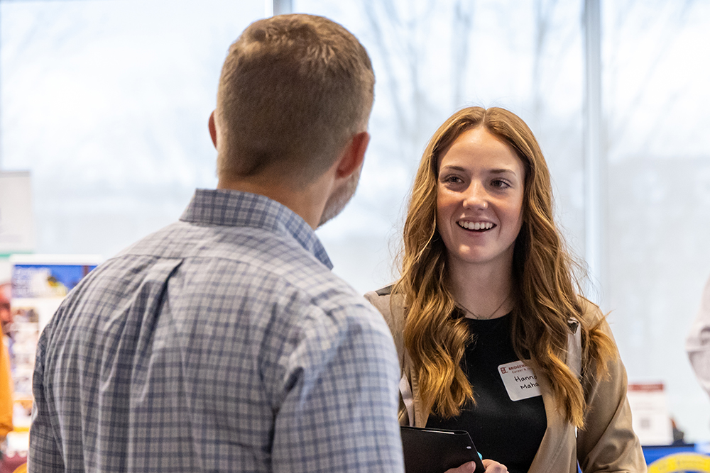 student with long red hair talking to recruiter at a career fair