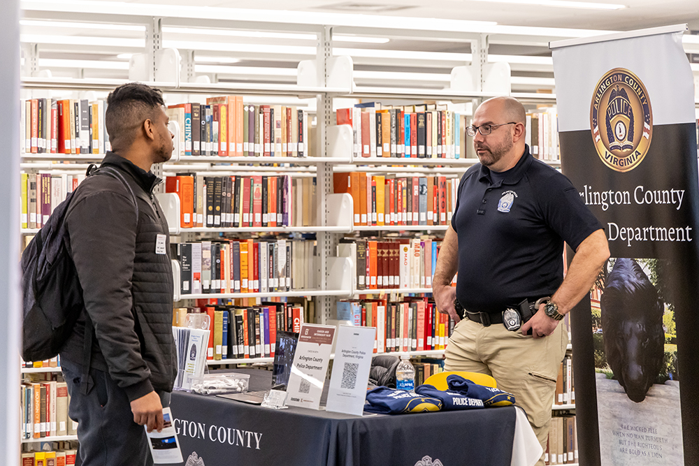 Student speaking with representative of police department at career fair