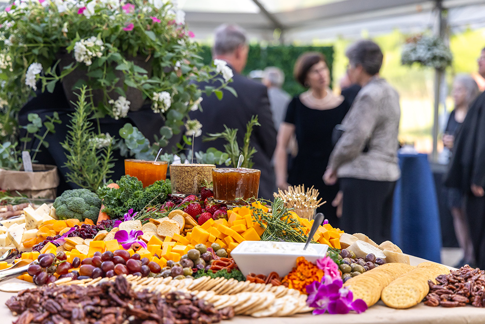 spread of meats, cheeses and crackers with people blurred in the background