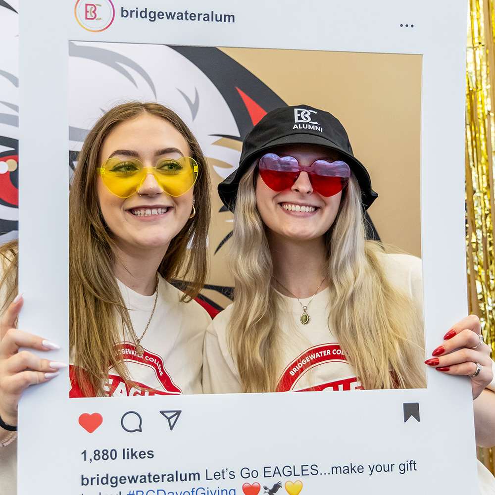 Two students with heart glasses holding Instagram photobooth prop