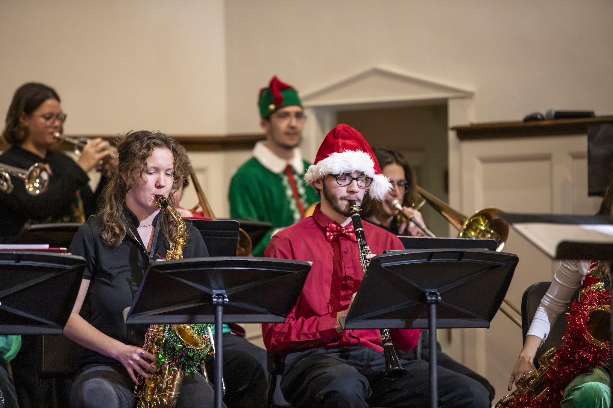 Students in Christmas-themed outfits playing music on stage.