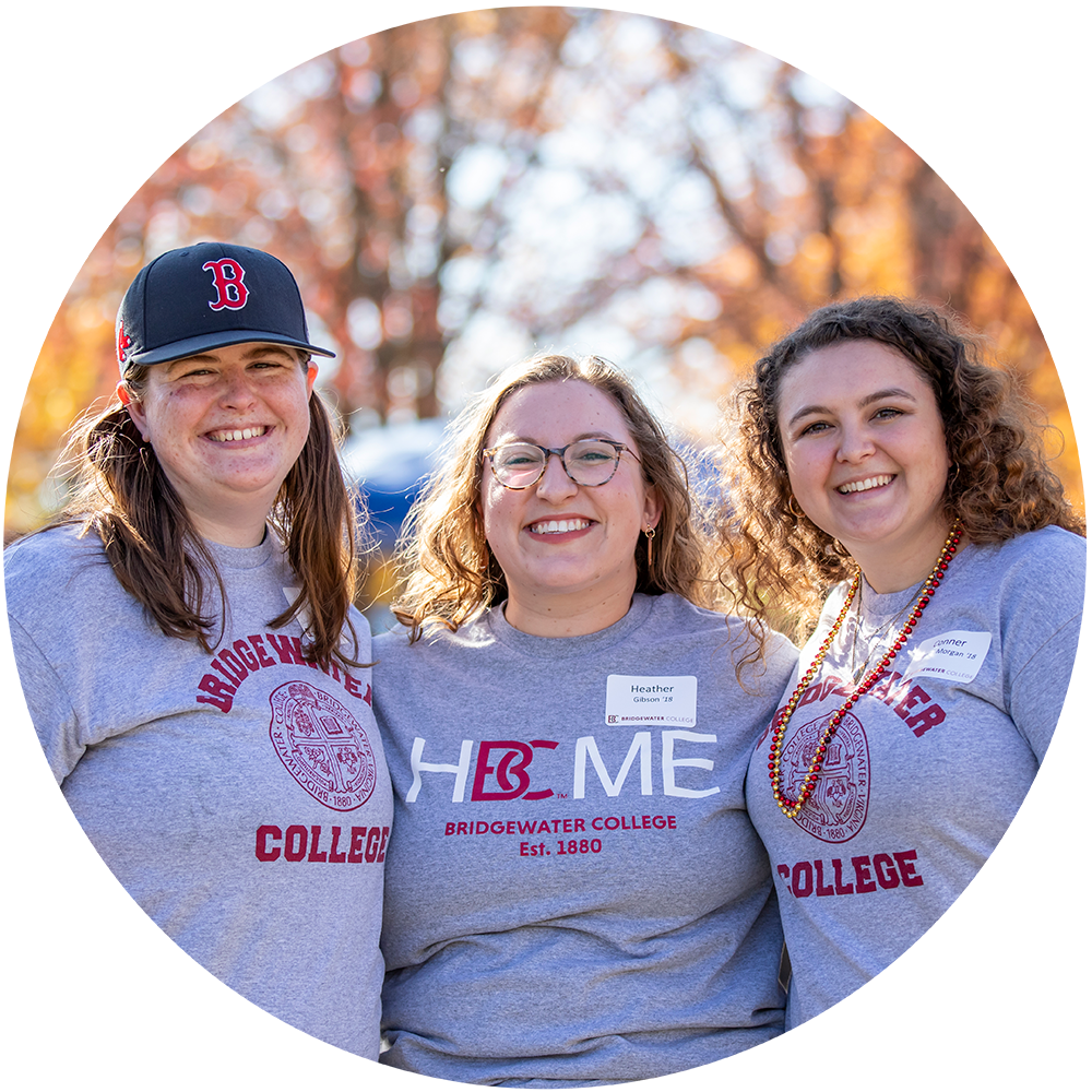 Three ladies smiling for the camera wearing grey Bridgewater College t-shirts