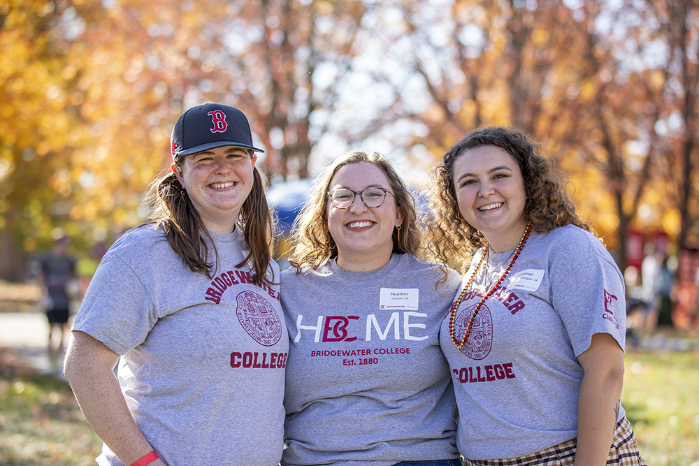 Three ladies smiling for the camera wearing grey Bridgewater College t-shirts