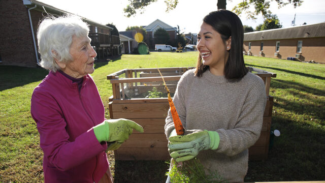 Student working in a garden with an elderly woman