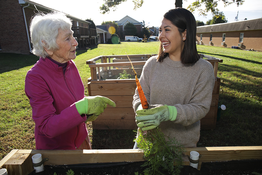 Student working in a garden with an elderly woman