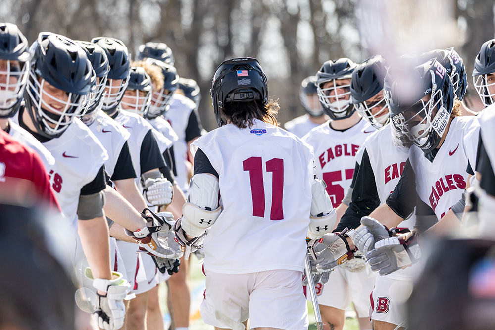 Men's lacrosse player number 11 running through line of other players