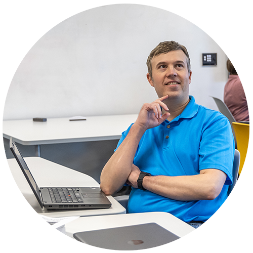 Non-profit management student sitting in front of a laptop looking up with hand on chin