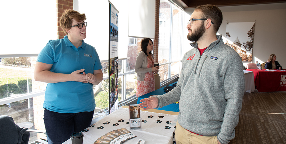 Non-profit Management graduate degree feature image - Two people talking at a fair with information about the R-H S-P-C-A