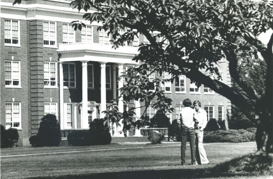 Black-and-white photograph showing students standing under a tree