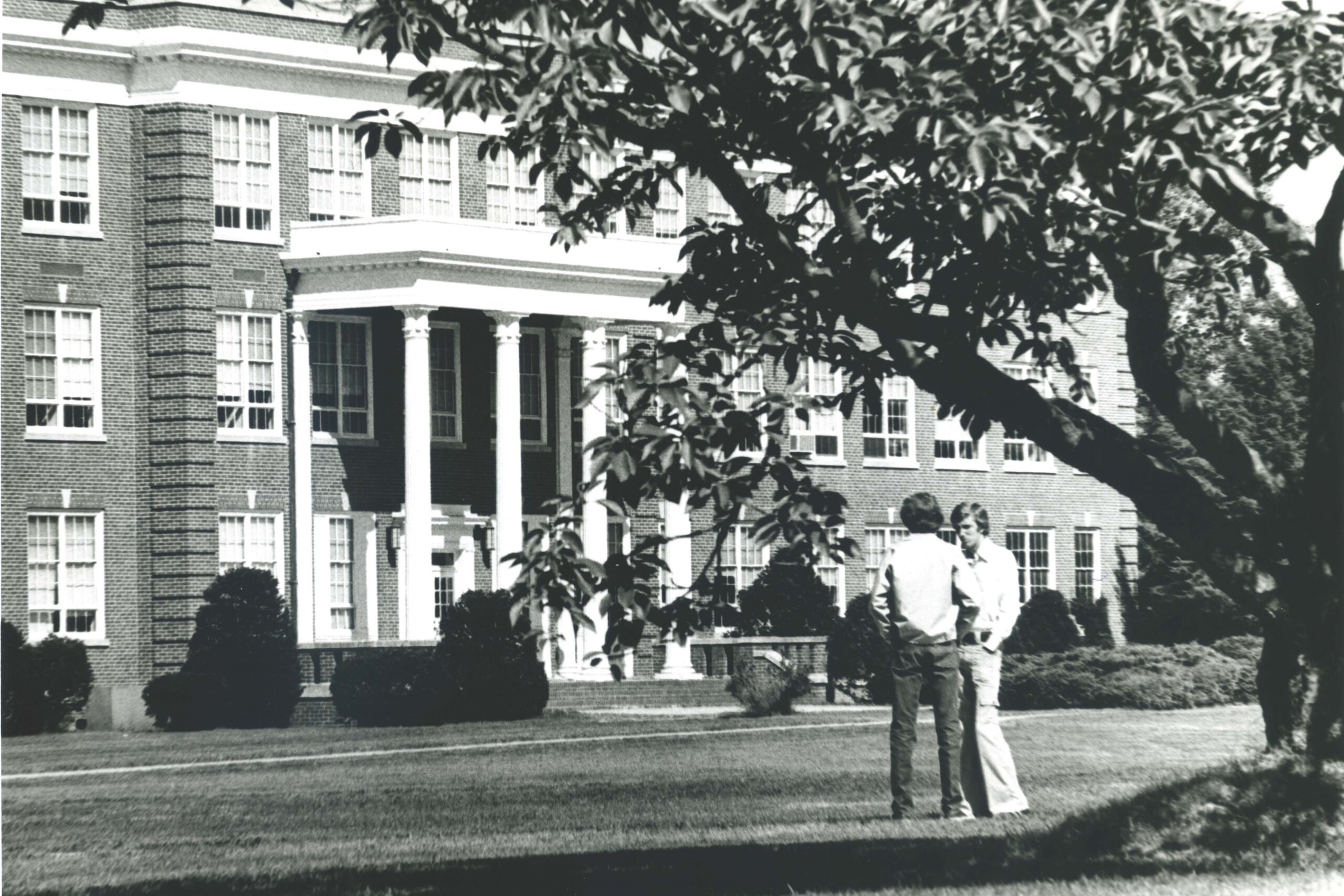 Black-and-white photograph showing students standing under a tree