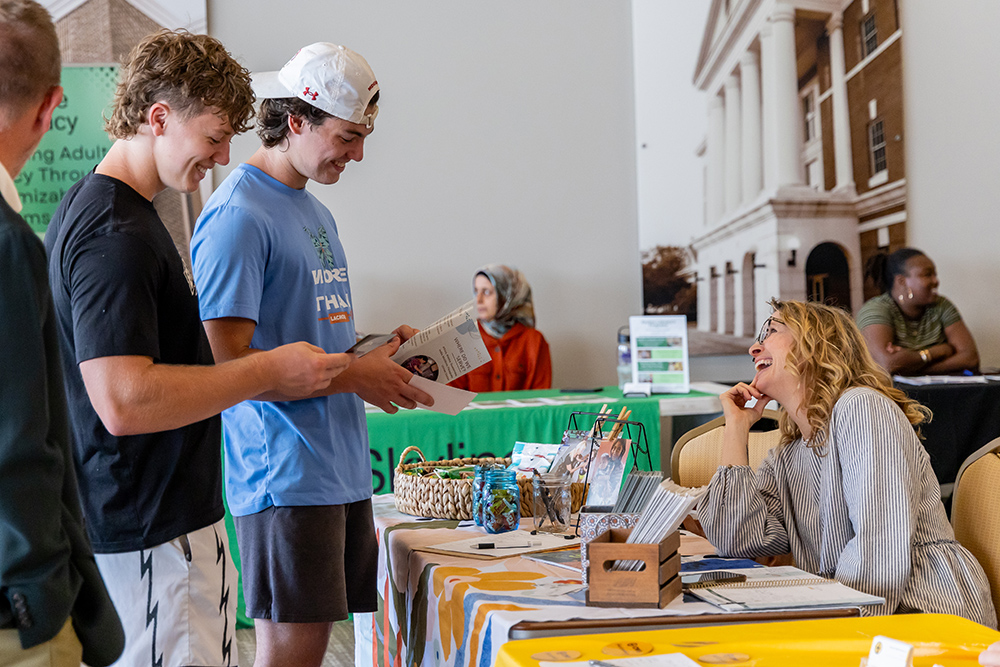 Students laughing with someone representing a non-profit at the volunteer and service fair