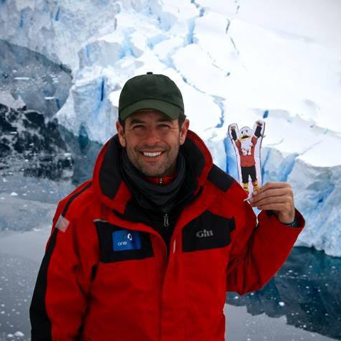 Man holding Flat Ernie in front of glacier in Antartica