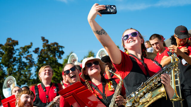 Members of Screamin' Eagles Marching Band in the stands taking a selfie