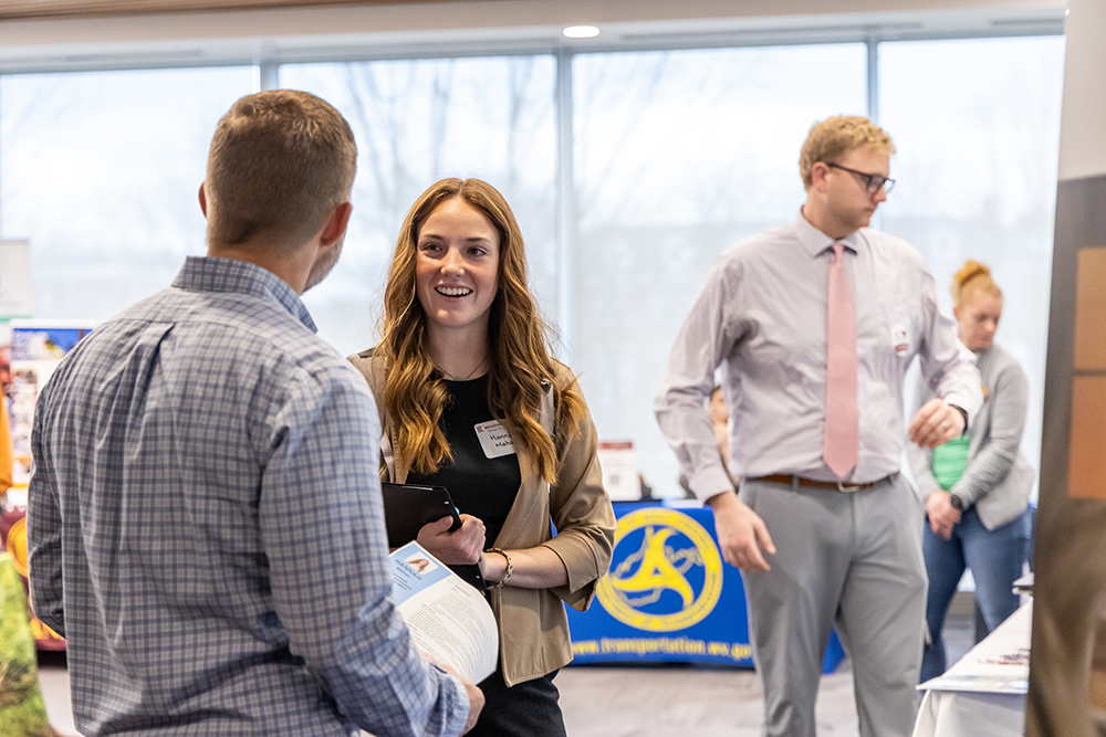 student with long red hair talking to recruiter at a career fair