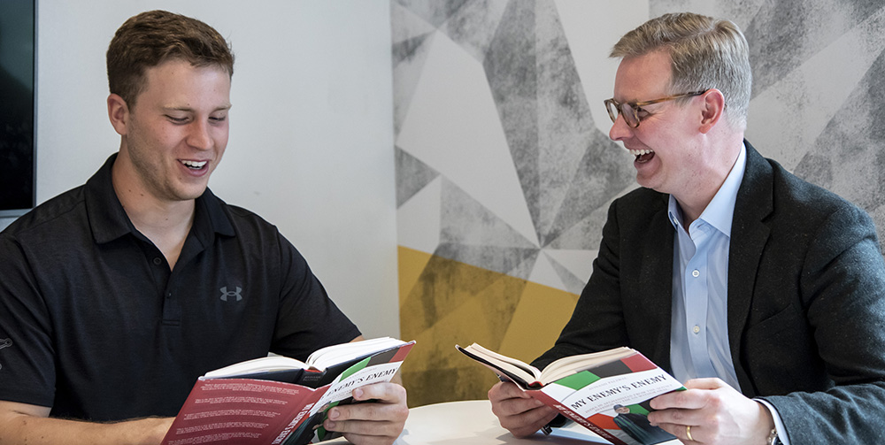 Alex Schwind '22 and Brandon Marsh sitting discussing a book they are both holding