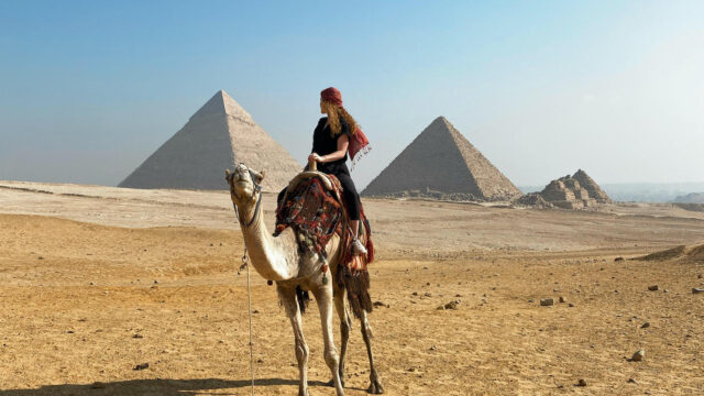 Study abroad participant in Egypt with pyramids in background.