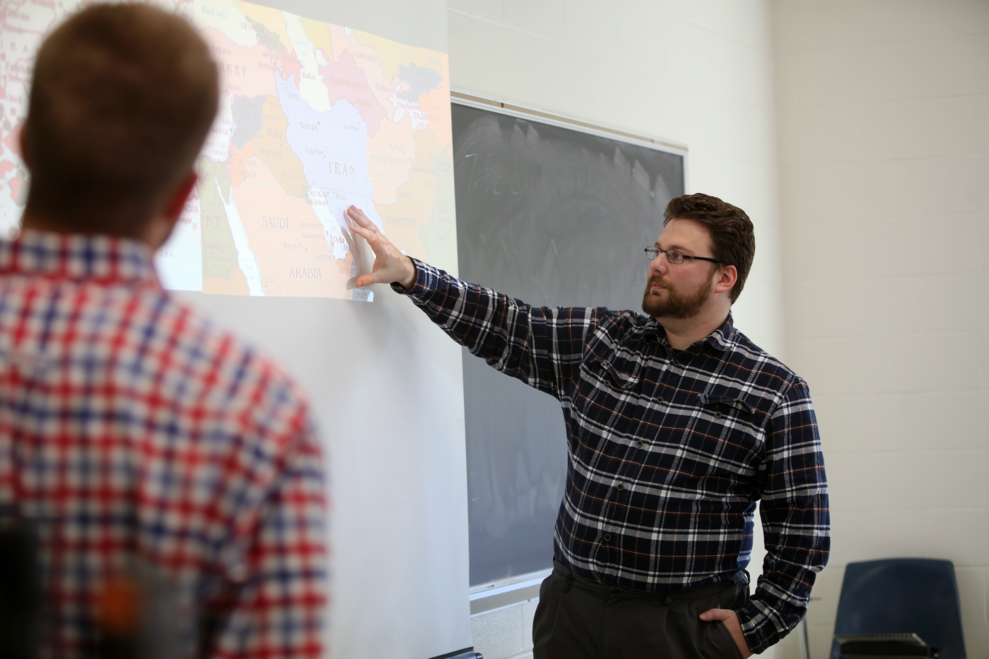 Student standing pointing to map projected on a screen