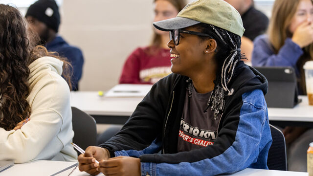 Student wearing a hat smiling in a sociology class