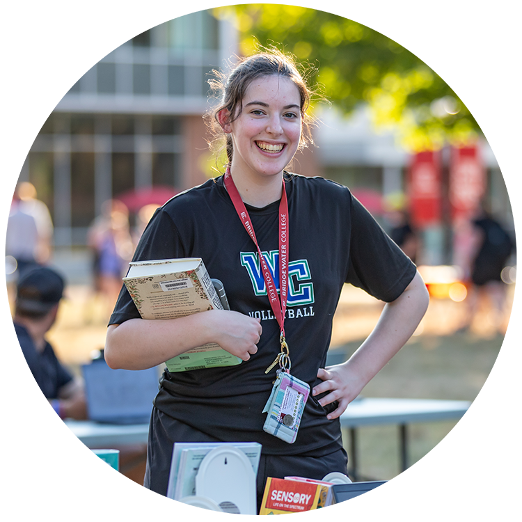 Student with a book in her arms smiling for the camera 